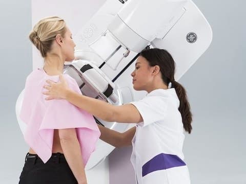 Technologist positioning a patient at a 3D mammography unit